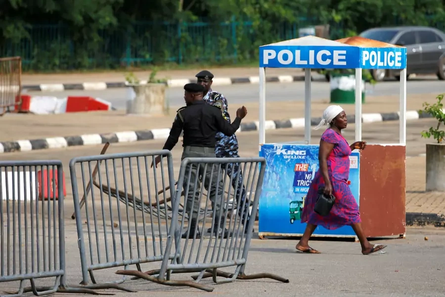 A woman walks past police officers outside the National Assembly, after clashes between police and a group of Shiite protesters in Abuja, Nigeria, on July 9, 2019.