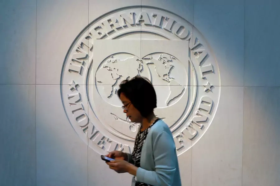 A woman walks past the International Monetary Fund (IMF) logo at its headquarters in Washington, U.S., May 10, 2018. 