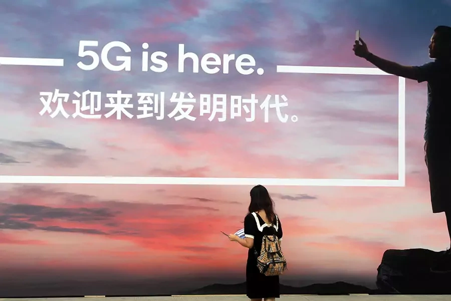 A woman walks past a billboard reading '5G is here' on day one of the Mobile World Congress (MWC) Shanghai 2019 at the Shanghai New International Expo Center on June 26, 2019 in Shanghai, China. 