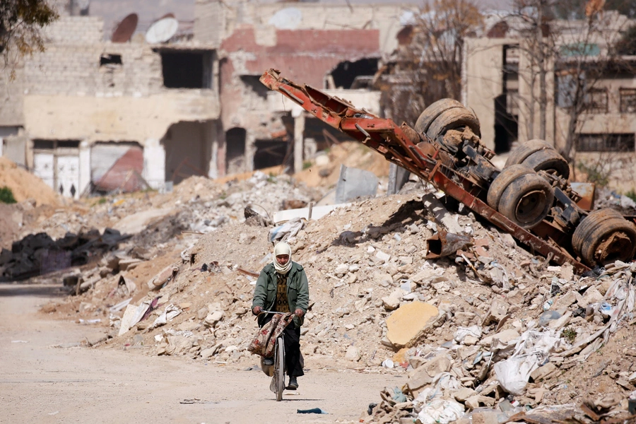 A man rides on a bike past rubble in Ein Terma, a district of eastern Ghouta, Syria, on February 26, 2019