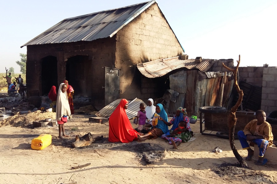 People sit near a burnt house after an attack by suspected members of the Islamist Boko Haram insurgency in Bulabulin village, Nigeria, on November 1, 2018.
