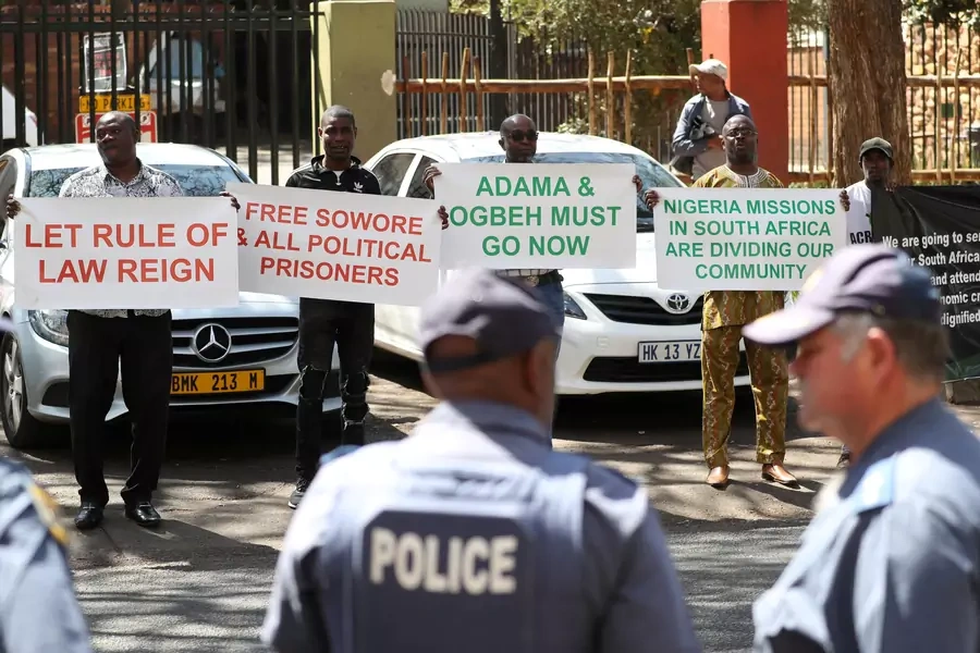 Police officers look on as Nigerians living in South Africa hold placards in protest against President Muhammadu Buhari, as he holds town hall meeting with diaspora living in South Africa following recent xenophobic attacks, in Pretoria, South Africa, Oct
