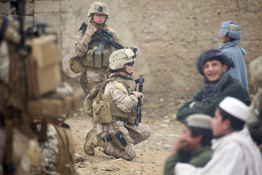 U.S. Marine Corps Lance Cpl. Sienna De Santis and U.S. Navy Petty Officer 3rd Class Heidi Dean, both with Female Engagement Team, greet children during a patrol in Sangin Valley, Afghanistan, 2010.