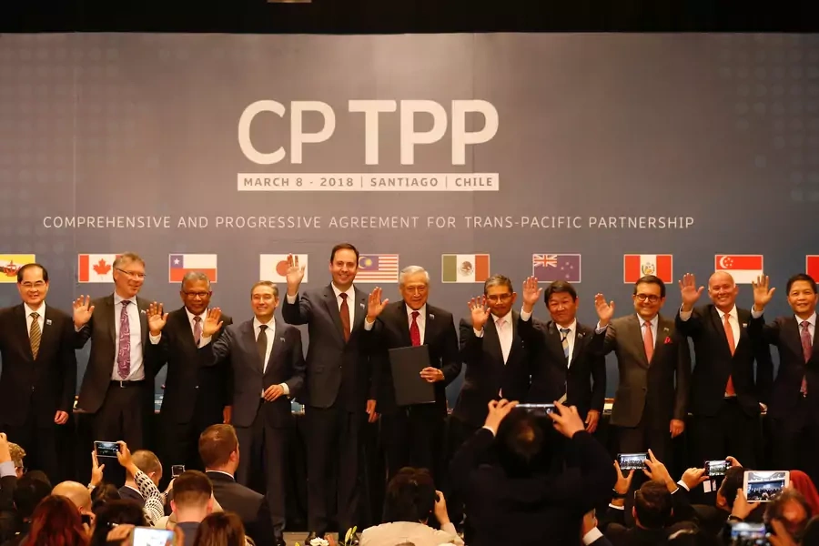Representatives of members of Trans-Pacific Partnership (TPP) trade deal wave as they pose for an official picture after the signing agreement ceremony in Santiago, Chile March 8, 2018.