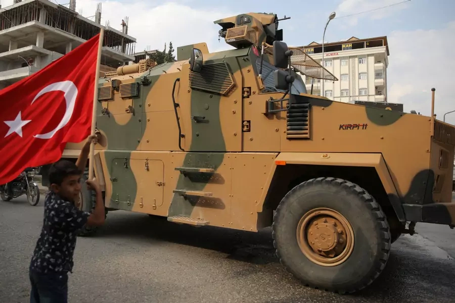 A boy waves a Turkish flag as a Turkish military vehicle drives through a town near the Turkey-Syria border on October 16. 