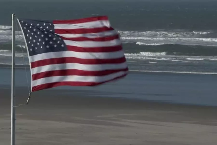 An American flag flies on the edge of the Atlantic ocean. 