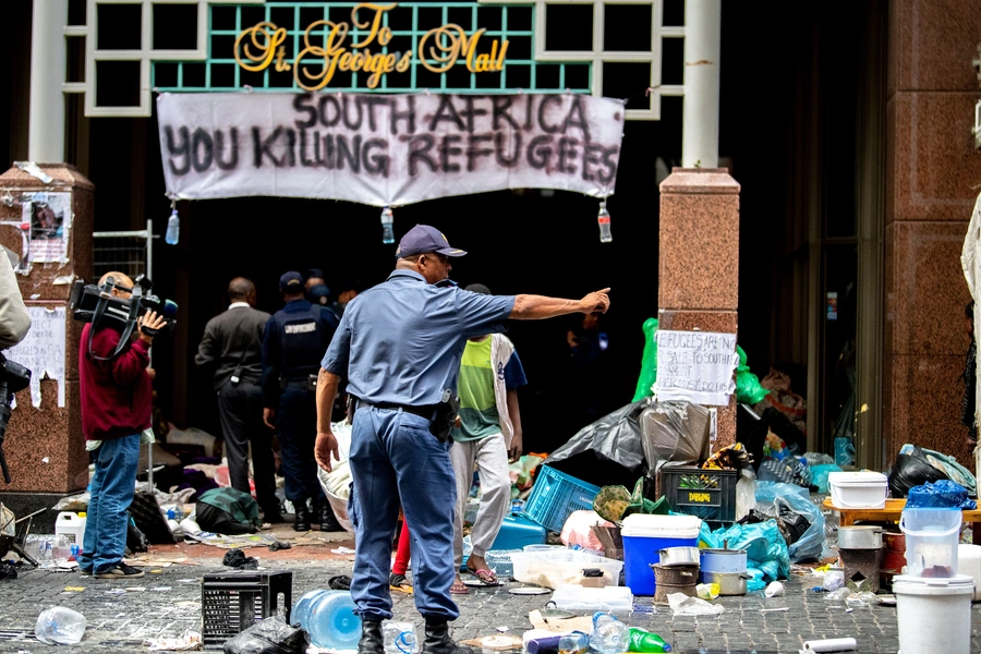 South African police officer gestures as they forcefully remove refugees from various countries who were camping outside the Cape Town offices of the United Nations Council for Refugees, in Cape Town on October 30, 2019.