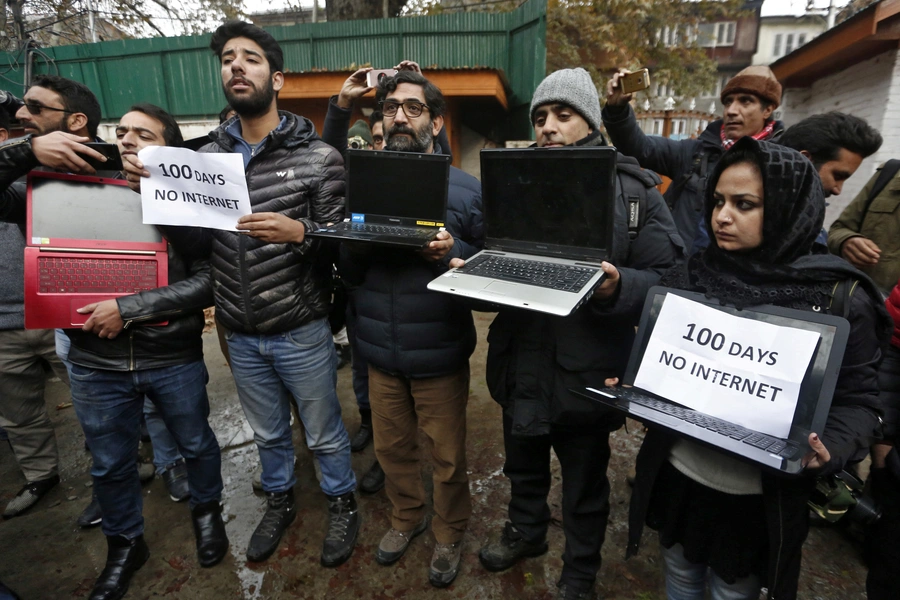 Kashmiri journalists display laptops and placards during a protest demanding restoration of internet service, in Srinagar