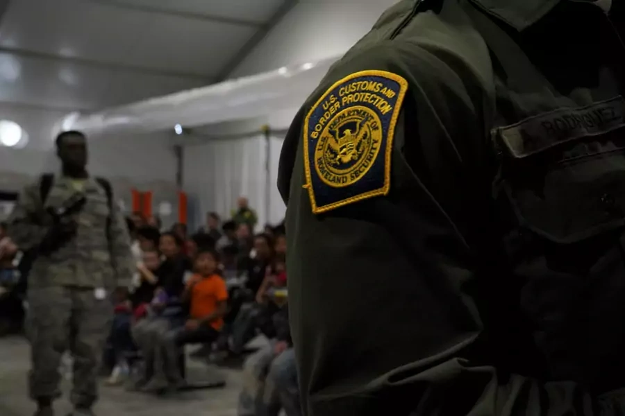 A U.S. Customs and Border Patrol officer stands by migrants at a processing facility in Donna, Texas. 