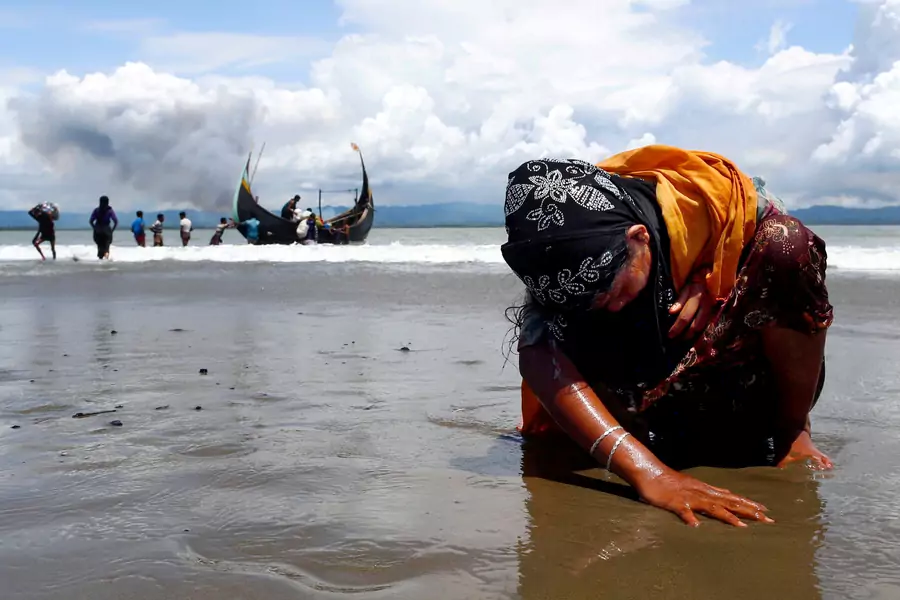 A Rohingya refugee woman touches the shore after crossing the Bangladesh-Myanmar border by boat. September 11, 2017. 