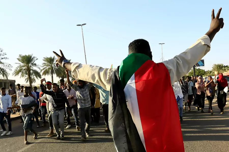 A Sudanese man wears a national flag and flashes the victory sign as people gather during the first anniversary of the start of the uprising that toppled long-time ruler Omar al-Bashir, in Khartoum, Sudan December 19, 2019