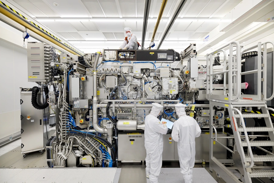 Employees are seen working on the final assembly of ASML's TWINSCAN NXE:3400B semiconductor lithography tool with its panels removed