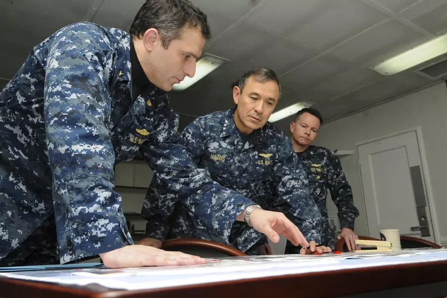 Vice Adm. Harry B. Harris Jr. receives an overnight situation report aboard the command ship USS Mount Whitney on March 24, 2011. REUTERS
