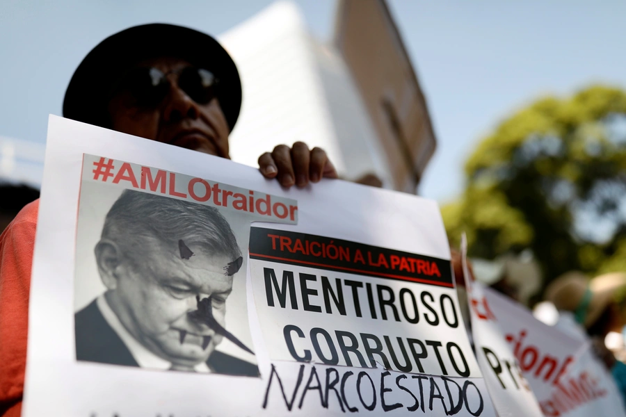 A demonstrator holds a sign during a march against Mexico's president Andres Manuel Lopez Obrador as he delivers his first state of the union in Mexico City, Mexico, September 1, 2019. The sign reads, "#AMLO traitor. Liar. Corrupt. Narco-state".