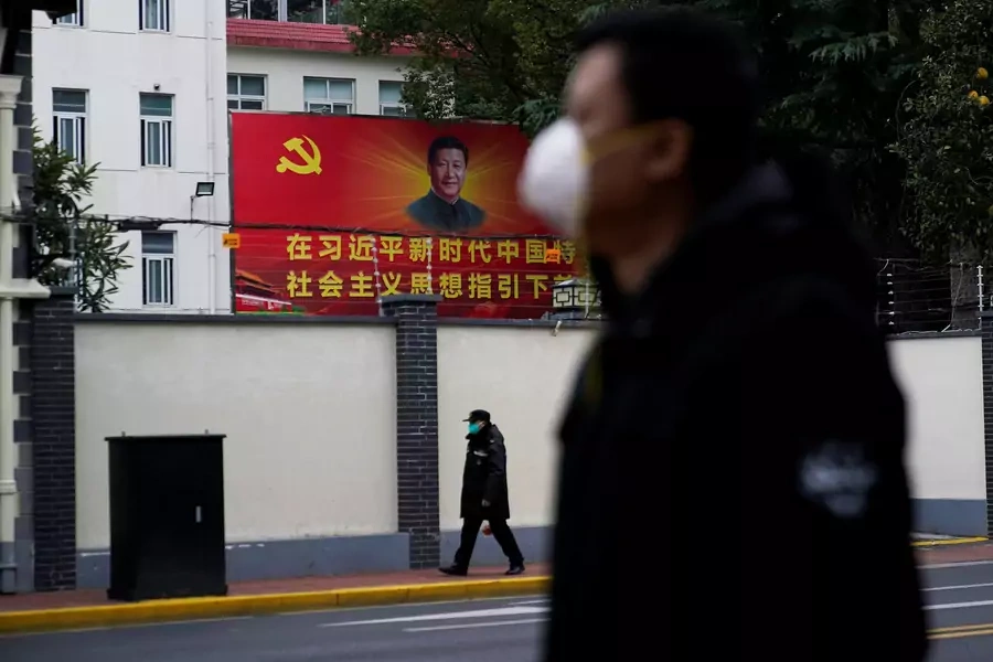 People wearing masks walk past a portrait of Chinese President Xi Jinping on a street as the country is hit by an outbreak of the novel coronavirus in Shanghai.