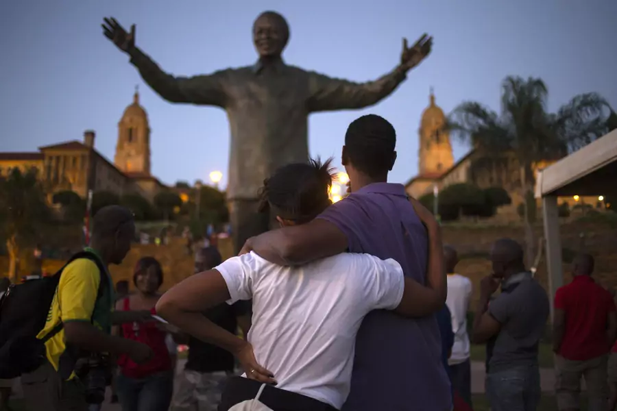 A couple stands near a bronze statue of late former South African President Nelson Mandela hours after it was unveiled as part of Day of Reconciliation celebrations at the Union Buildings in Pretoria, on December 16, 2013.