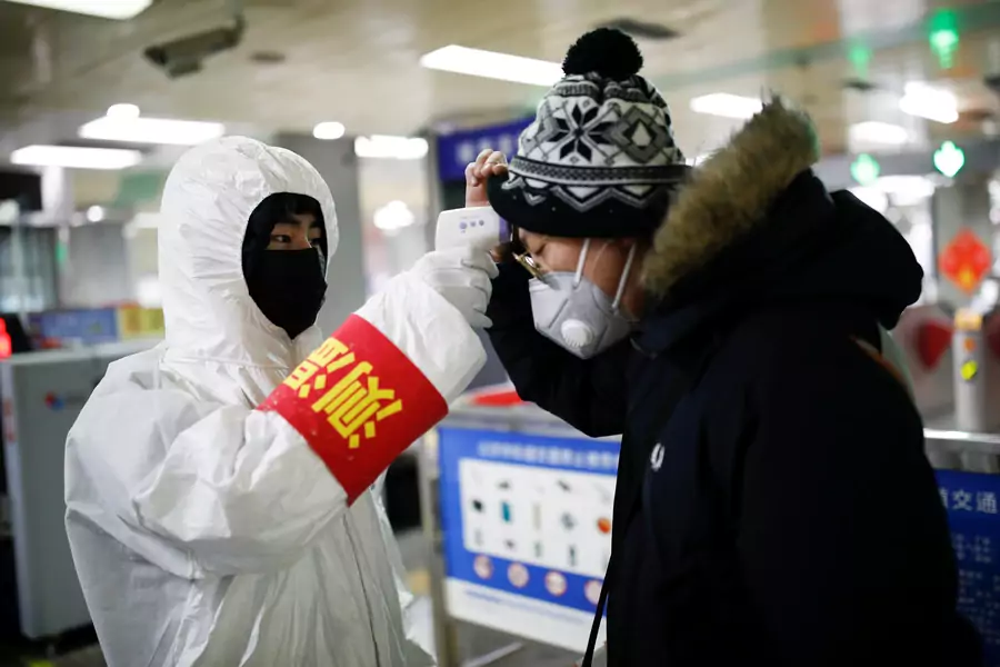 A staff member checks the temperature of a passenger entering a subway station, as the country is hit by an outbreak of the new coronavirus, in Beijing, China