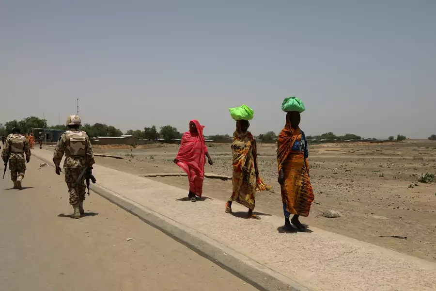 Women walk past soldiers on a bridge separating Cameroon and Nigeria, in Gamboru Ngala, Borno, Nigeria, on April 27, 2017