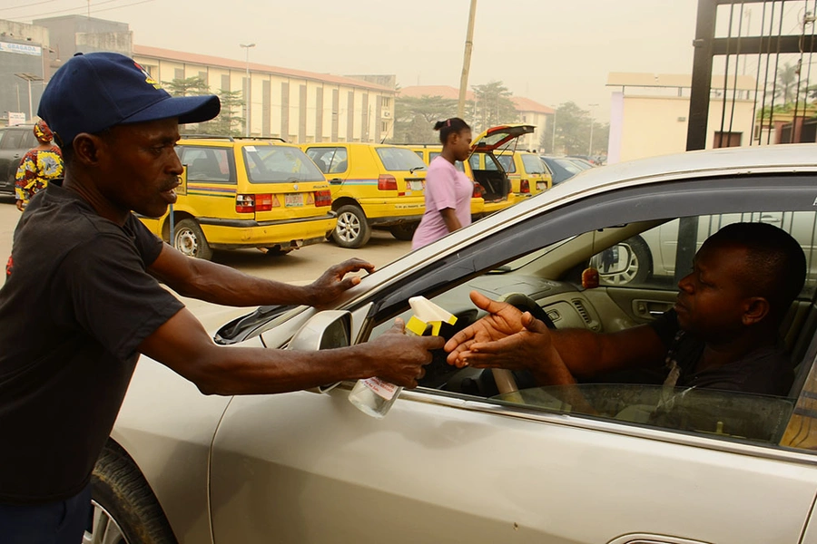 A Nigerian Security and Civil Defence Corps official spray a man hand with hand sanitizer in front of Gbagada General Hospital, after Lassa fever outbreak death toll hits 70 in Nigeria, in Lagos February 14, 2020.