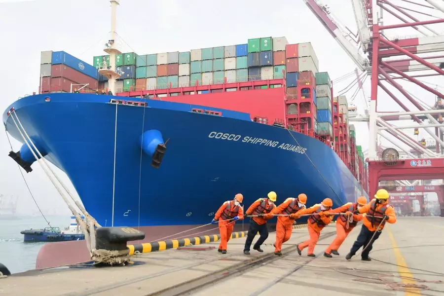 Workers wearing face masks rope a container ship at a port in Qingdao, Shandong province, China February 11, 2020.