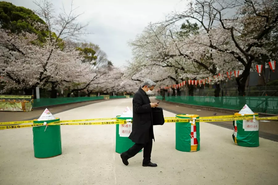 A man wearing a face mask, following an outbreak of COVID-19, walks past a closed cherry blossom viewing spot during the first weekend after Tokyo Governor Yuriko Koike (not pictured) urged Tokyo residents to stay indoors.