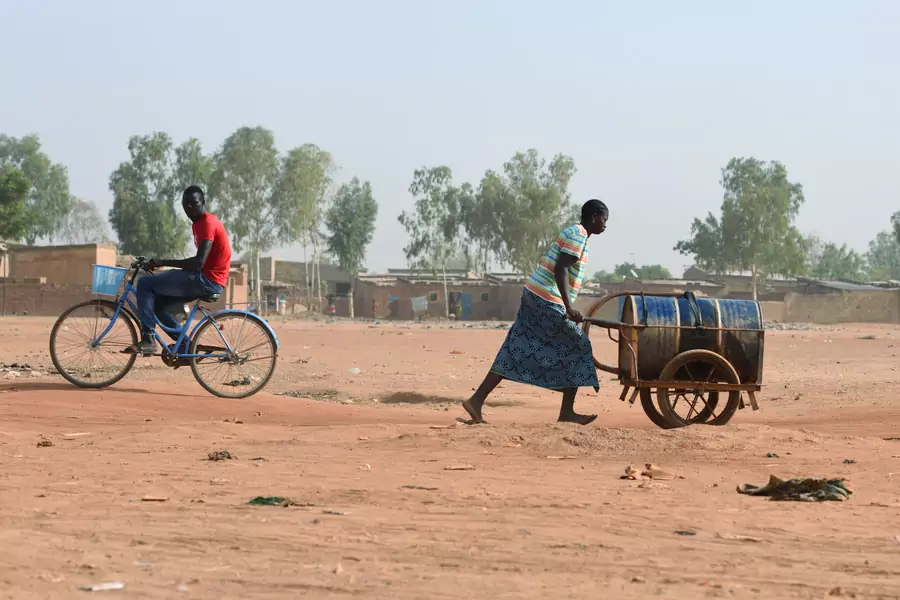 A woman pushes a barrel filled with water she bought from a privately-owned water tower, amid an outbreak of the coronavirus disease (COVID-19), in Taabtenga district of Ouagadougou, Burkina Faso, on April 3, 2020.