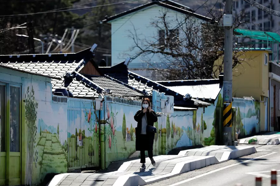 A woman wearing a protective mask following an outbreak of COVID-19 walks through downtown Cheongdo County, near Daegu, South Korea, on March 11, 2020.