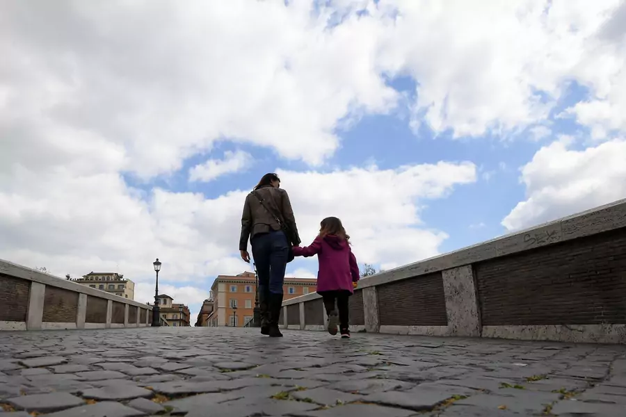 A woman walks on the Ponte Sisto with her daughter in the Trastevere district as the spread of coronavirus disease (COVID-19) continues, in Rome, Italy, April 2, 2020.