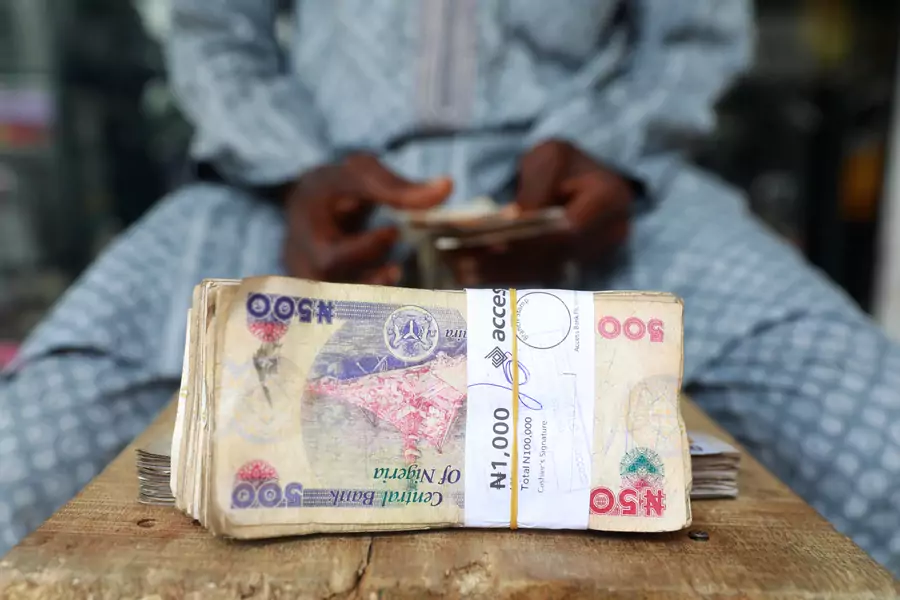 A money changer counts Nigerian currency notes for a customer in Nigeria's commercial capital, Lagos, Nigeria, on March 16, 2020.