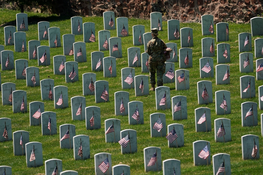 An Old Guard places flags in front of headstones at Arlington National Cemetery on May 23, 2019. Kevin Lama/REUTERS