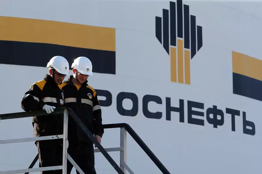 Workers stand next to a logo of Russia's Rosneft oil company at the central processing facility of the Rosneft-owned Priobskoye oil field outside the West Siberian city of Nefteyugansk, Russia.