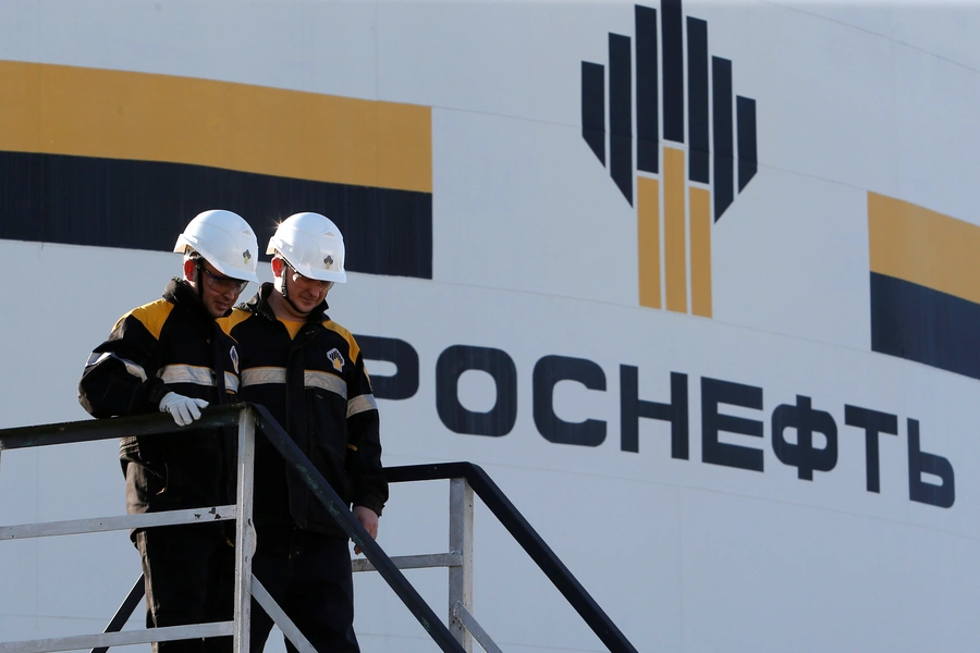 Workers stand next to a logo of Russia's Rosneft oil company at the central processing facility of the Rosneft-owned Priobskoye oil field outside the West Siberian city of Nefteyugansk, Russia.