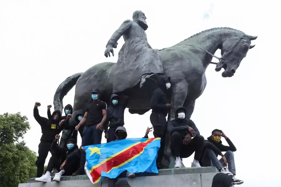 Demonstrators stand on the statue of Leopold II as one of them holds a national flag of the Democratic Republic of Congo during a protest, organised by Black Lives Matter Belgium, in Brussels, Belgium, on June 7, 2020.
