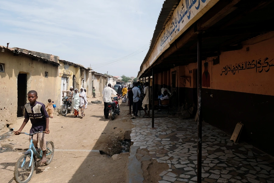 People pass by the site of Mallam Nigas’s Islamic school and rehabilitation center, which was raided by police last week, in Katsina, Nigeria, on October 18, 2019.