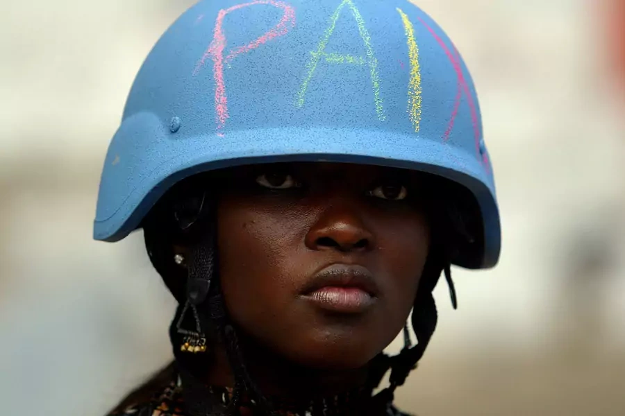 A U.N. worker wears a U.N. helmet with the word "peace" written on it in Martissant, Haiti.