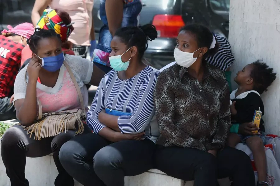 Ethiopian domestic workers wearing masks stand with their belongings in front of the Ethiopian consulate in Lebanon, June 8, 2020.