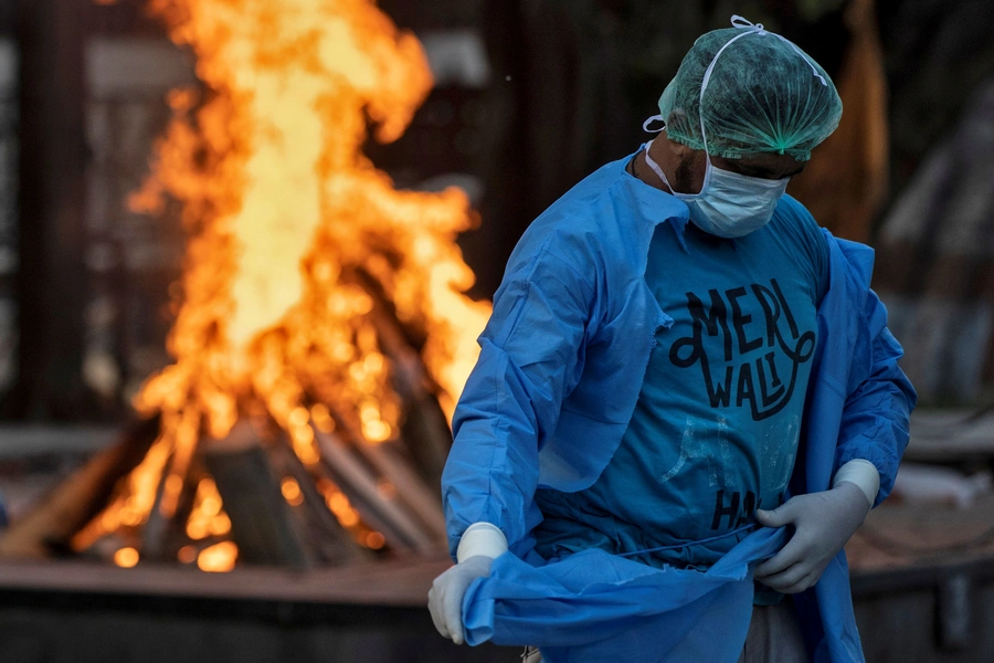 An ambulance driver, Mohammad Aamir Khan, changes his personal protective equipment at a crematorium in New Delhi.