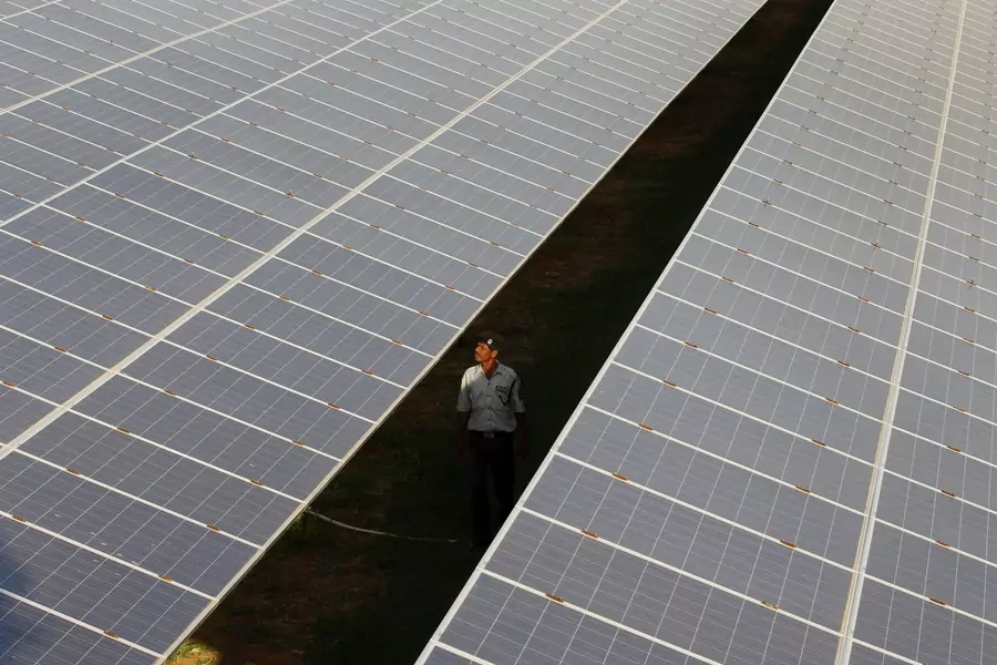 A private security guard walks between rows of photovoltaic solar panels inside a solar power plant at Raisan village near Gandhinagar, in the western Indian state of Gujarat, February 11, 2014.