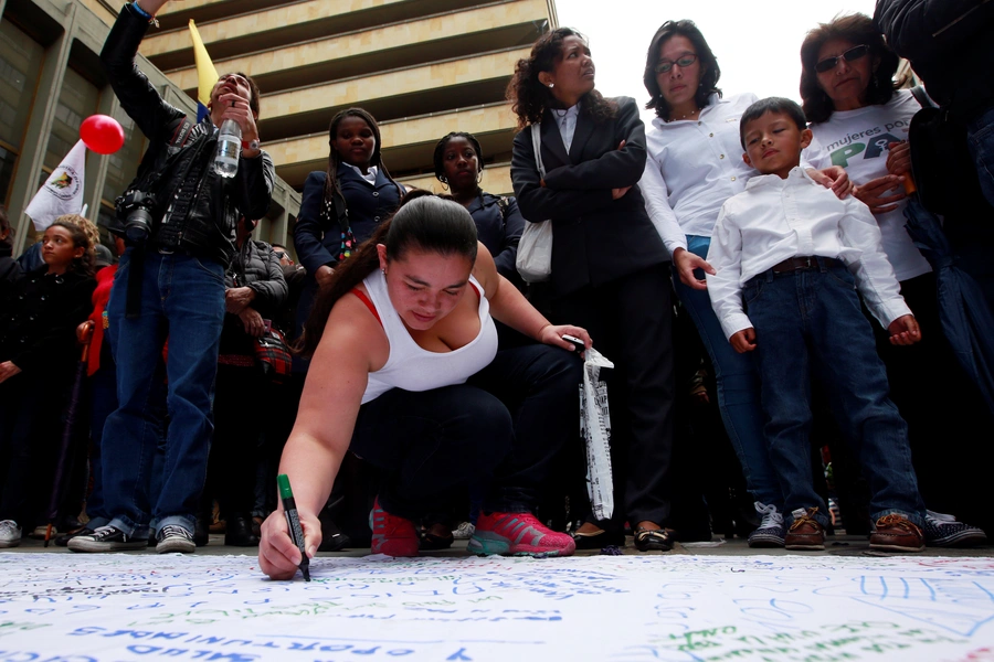 A woman writes a message about peace on a banner as people celebrate the signing of a historic ceasefire deal between the Colombian government and FARC rebels in Bogota, Colombia, June 23, 2016. 