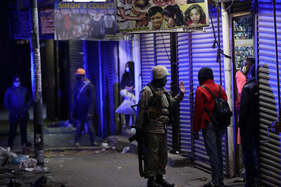 A member of the South African military talks to a man during a patrol as a nighttime curfew is reimposed amid a nationwide coronavirus disease lockdown, in Johannesburg, South Africa, on July 13, 2020. 