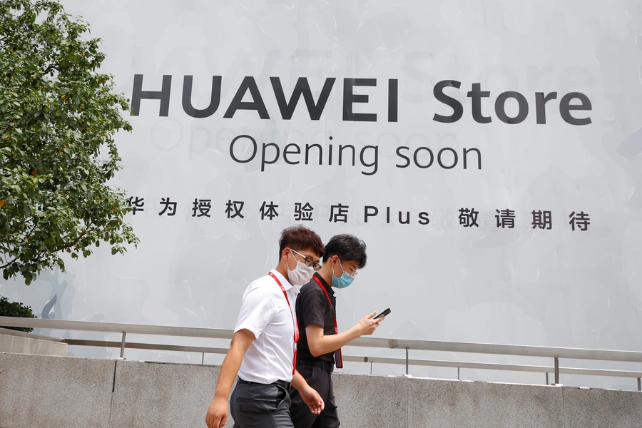 People walk past an advertisement announcing the opening of a Huawei store.