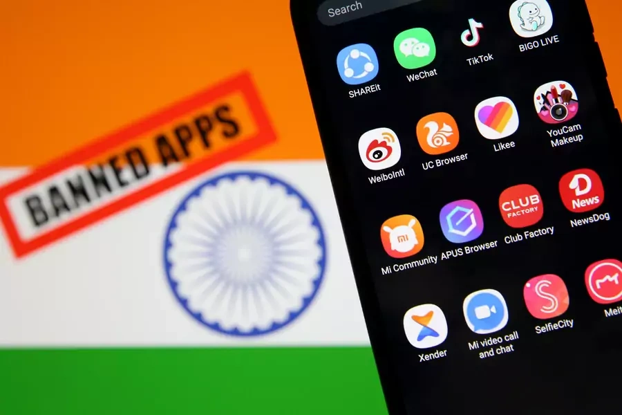 Smartphone with Chinese applications is seen in front of a displayed Indian flag and a "Banned app" sign.