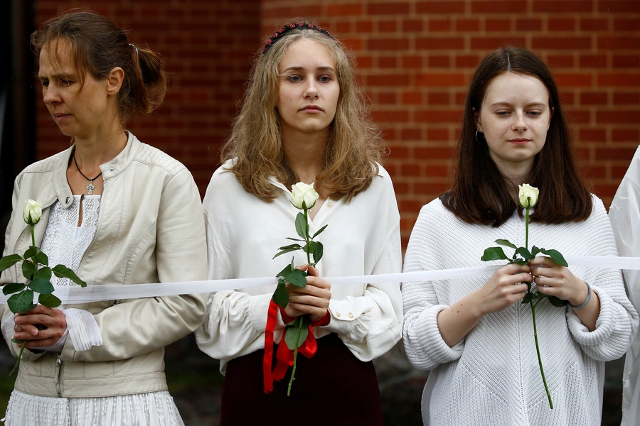 Women hold flowers as they participate in a rally against presidential election results at the Independence Square in Minsk, Belarus. August 27, 2020.