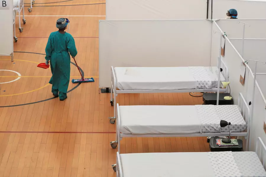 A health worker walks between beds at a temporary field hospital set up in a sports complex by Medecins Sans Frontieres (MSF) during the coronavirus disease (COVID-19) outbreak in Khayelitsha township near Cape Town, South Africa, on July 21, 2020.