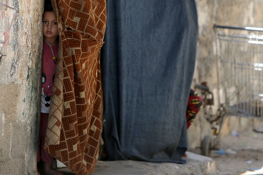 A Palestinian girl looks out of her family home as she watches members of Hamas security forces participating in a simulation exercise for preventing the spread of the coronavirus disease (COVID-19), in Gaza City July 18, 2020. REUTERS/Mohammed Salem