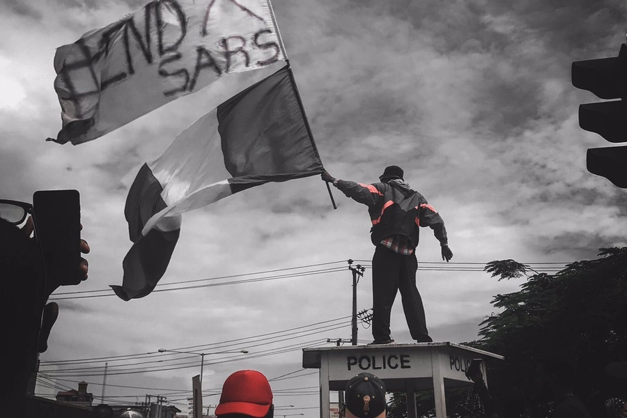 A protester stands atop a police structure in Ikeja, capital of Lagos state, during #EndSARS demonstrations on October 11, 2020.