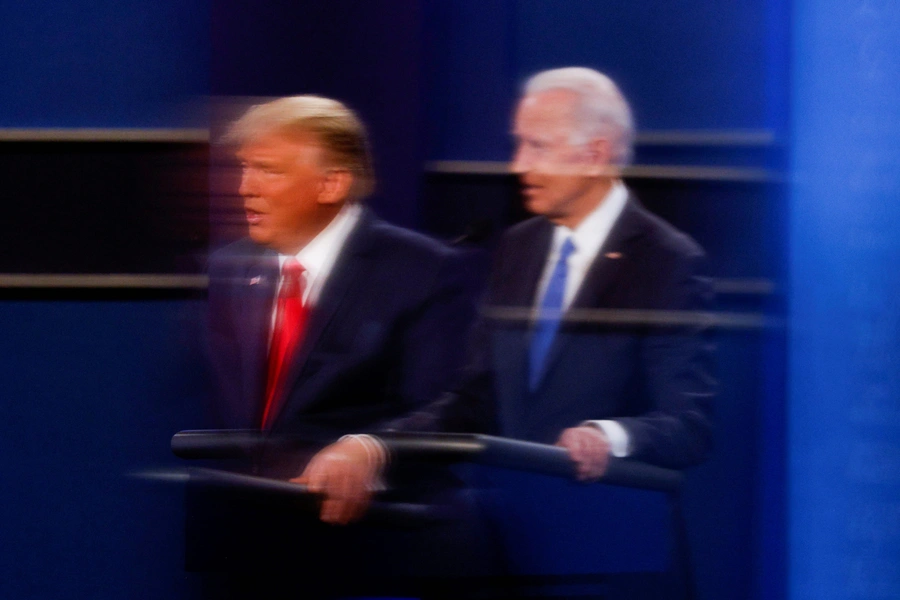 U.S. President Donald Trump and Democratic presidential nominee Joe Biden are reflected in the plexiglass protecting a TV camera operator from coronavirus as they participate in their second 2020 presidential campaign debate.