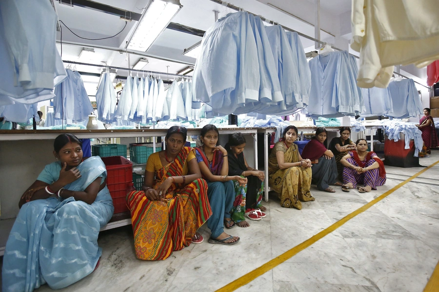 Employees sit during their lunch inside a textile mill of Orient Craft Ltd. at Gurgao in Haryana, May 5 2014