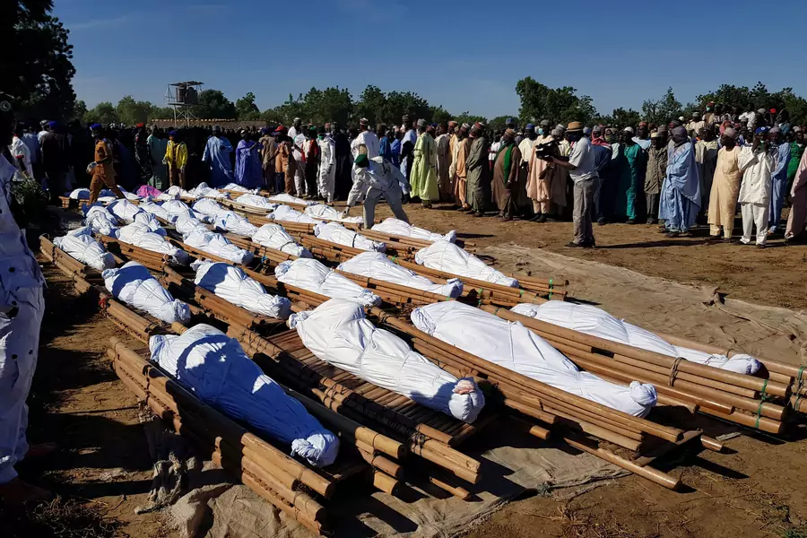 Men gather near dead bodies of people who were killed by militant attack, during a mass burial at Zabarmari, in the Jere local government area of Borno State, in northeast Nigeria, on November 29, 2020.