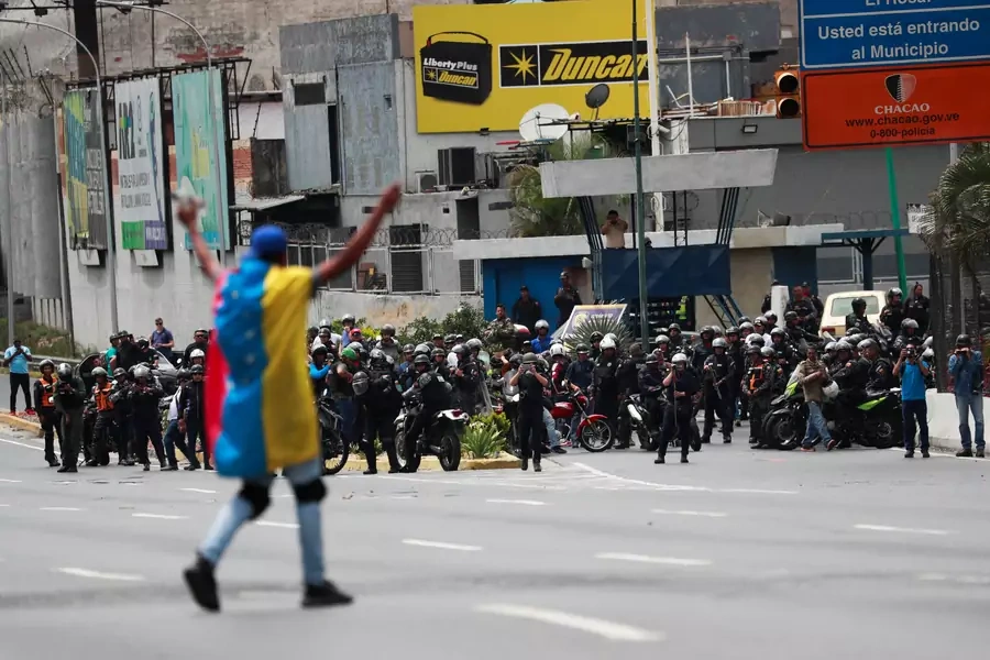 A demonstrator covered with a Venezuelan flag gestures in front of security forces during a protest in Caracas, Venezuela, on March 10, 2020.